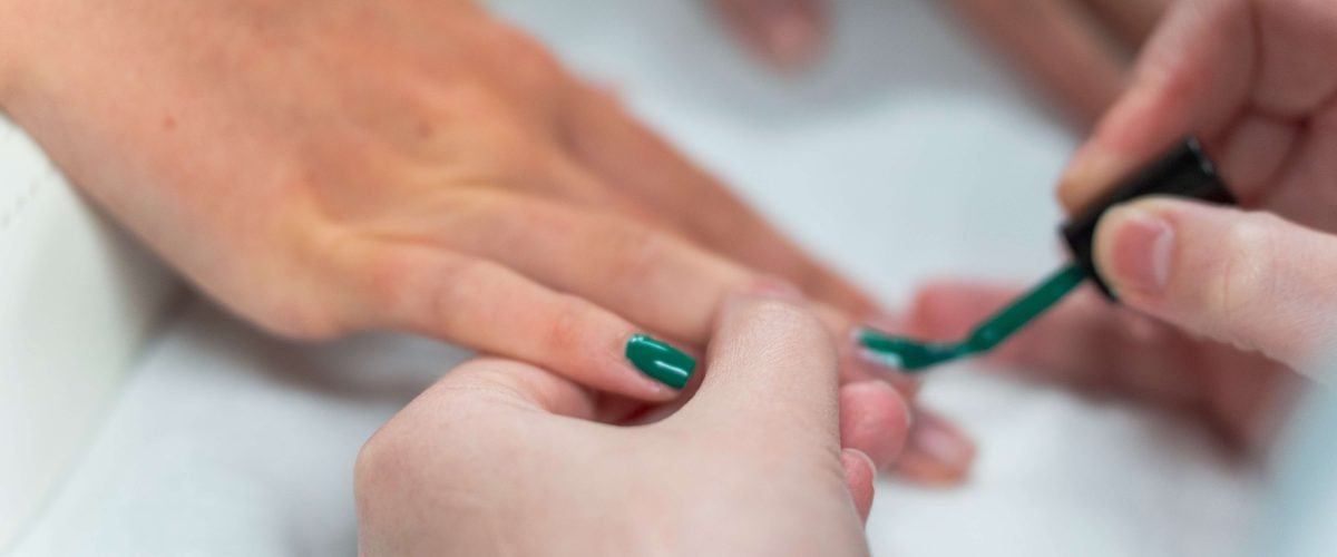 Close up of a student providing a nail treatment to a customer