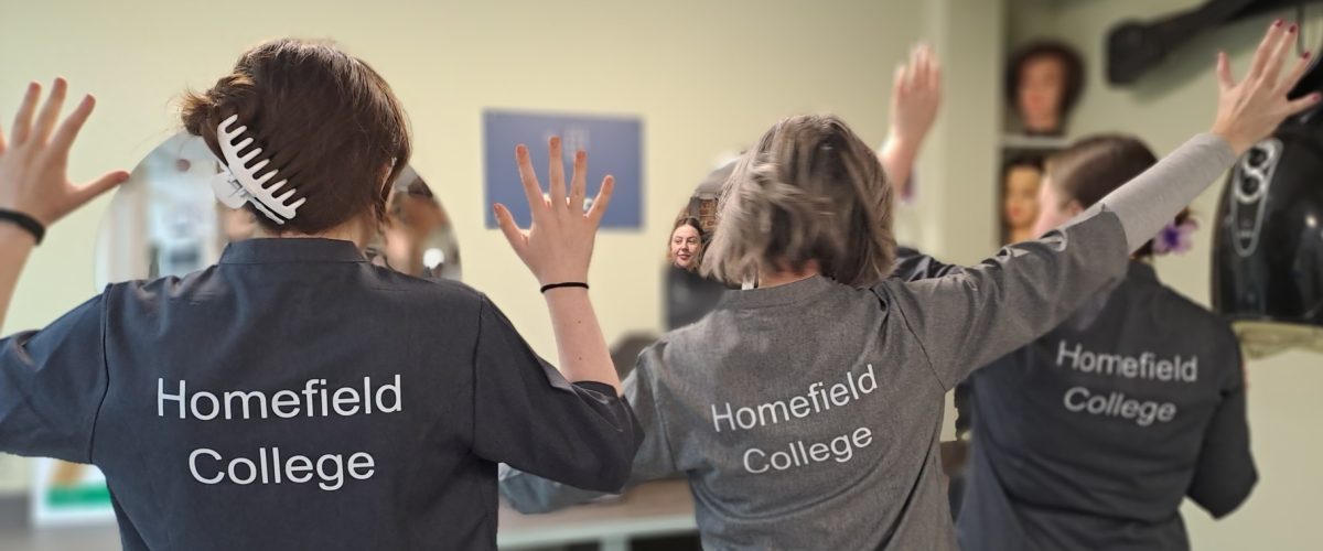 A picture of 3 Spectrum Style stylists with their backs to the camera, their shirts spelling "Homefield College"