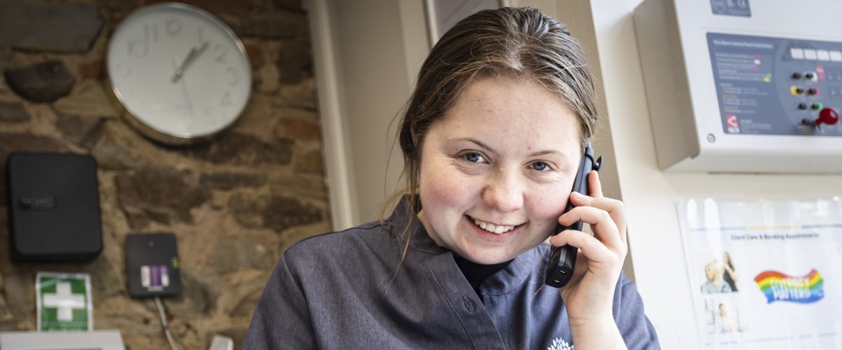 A student talking on the phone and booking in a client