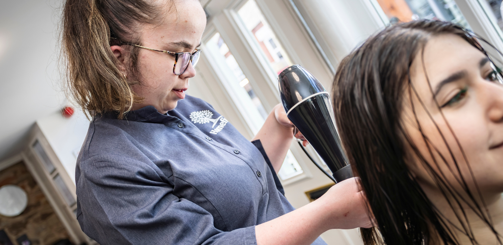 A female student blowdrying a client's hair